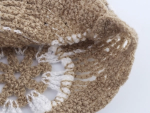 Close-up of khaki and white knitted fabric texture with hollowed structure details