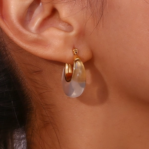 Close-up of fashionable amber and cream gradient resin hoop earrings with gold metal clasp