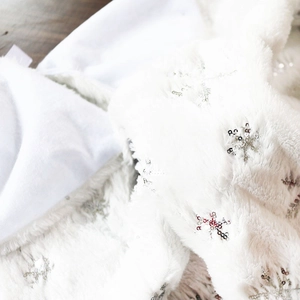 Close-up of white plush Christmas tree skirt with shimmering silver sequin snowflakes
