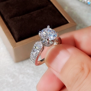 Macro shot of a classic four-prong round zircon engagement ring with pavé diamond band style