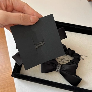 Close-up of black satin bow hair tie with sparkling rhinestone details on a display card