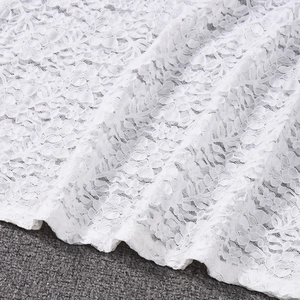 Close-up of white floral lace fabric with intricate embroidery and sheer mesh texture