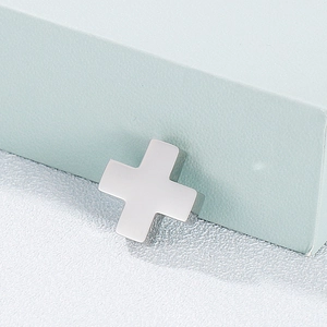Sleek silver stainless steel cross pendant displayed on a minimalist textured surface