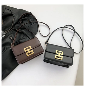 Detail view of stylish square bags in brown and black with gold geometric clasps
