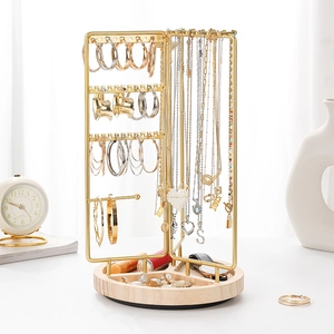 Rotating gold metal jewelry stand with wood base displaying necklaces and earrings