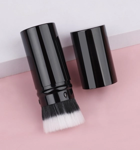Close-up of a black retractable makeup brush with synthetic fiber bristles and separate lid
