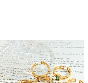 Close-up of gold layered open rings with emerald cut green gemstone and twisted bands