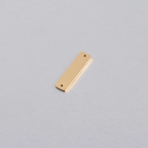 Macro shot of mirror-polished gold stainless steel rectangle tag with two holes for DIY jewelry
