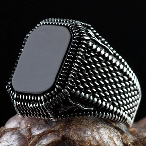 Macro detail of men's vintage copper ring with black stone on natural stone base