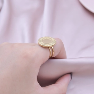 Detailed view of golden minimalist geometric ring with textured disc on a satin background