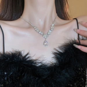 Close-up of sparkling teardrop rhinestone pendant necklace worn by a model