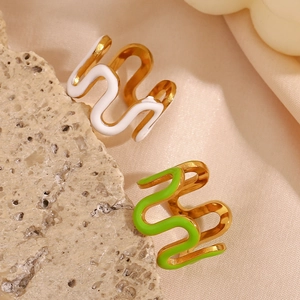 Detailed macro of gold-plated wavy rings with white and green enamel on silk fabric