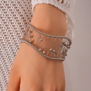 Gros plan d'un bracelet manchette argenté tressé avec maille évidée et perles métalliques