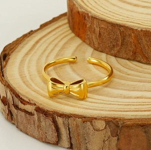 Detail of golden bow ring with brushed finish on natural wooden background texture