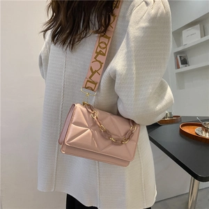 Pink quilted crossbody bag with wide logo strap and resin chain shown in a side view