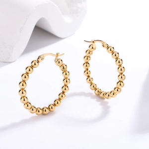 Detailed close-up of golden beaded hoop earrings with a polished spherical texture