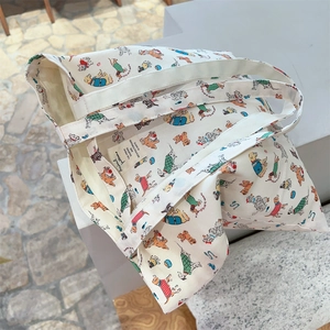 Close-up of cream canvas tote bag with cartoon dog prints and woven brand label