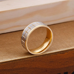 Macro detail of men's tire tread ring showing silver brushed finish and gold inner band