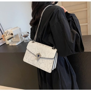Detail of white textured shoulder bag with silver chain and blue gemstone buckle
