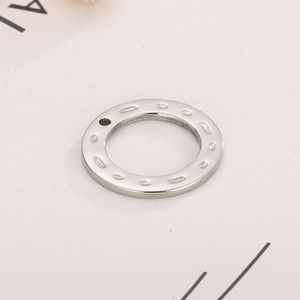 Close-up of silver stainless steel round charm with hammered texture and small hole