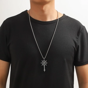 Détail d'un pendentif boussole et épée vintage sur une chaîne masculine en acier