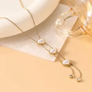 Detail of 18K gold tassels necklace featuring three white heart-shaped pearl pendants