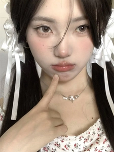 Close-up of elegant silver flower pendant necklace on model with white bow hairclip