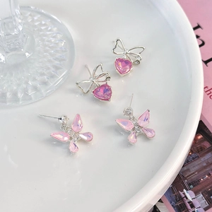 Detailansicht von rosa Schmetterlingskristall- und Herzperlenohrringen auf einem Keramikteller