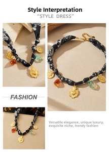 Detail of bohemian gold heart charms and amber beads on black printed fabric necklace
