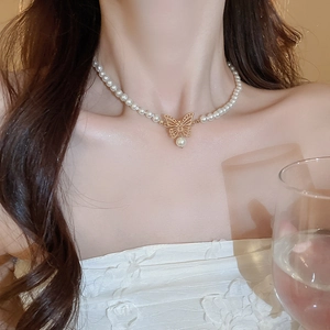 Choker élégant en perles blanches avec pendentif papillon doré sur une femme