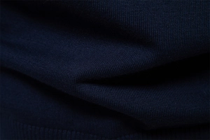 Macro detail of navy blue knit fabric texture on men's half-zip sweater with fine fibers