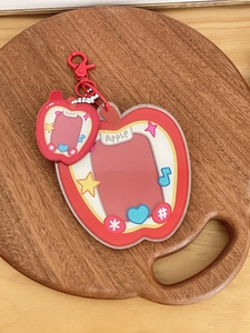 Detail of red apple acrylic card holder set with star motifs and silver bead chain