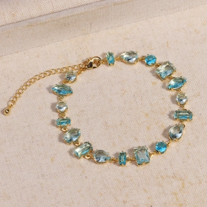 Gros plan détaillé d'un bracelet doré aux cristaux bleus sur fond de toile beige