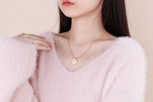 Detail of gold snake chain necklace with mother of pearl zodiac pendant on model