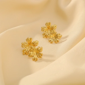 Polished 18K gold plated flower earrings with brushed metal texture in a warm studio shot