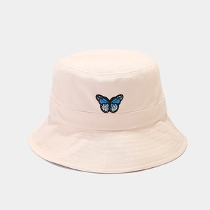 Close-up detail of blue and black butterfly embroidery on beige canvas bucket hat
