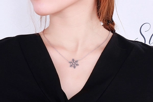 Detailed close-up of a silver snowflake pendant with intricate hollow design on a fine chain