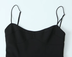 Détails de la robe noire à fines bretelles avec encolure incurvée et coutures précises
