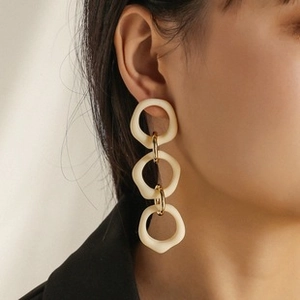 Detail shot of elegant cream-white resin triple hoop drop earrings on model