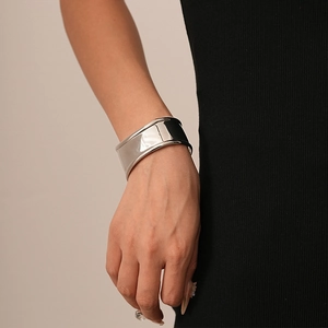 Close-up of minimalist silver wide cuff bracelet with smooth curved metallic surface