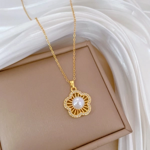 Macro shot of gold five-petal flower necklace with a pearl center and zircon pavé detail