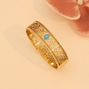 Detailed macro view of vintage hollow gold bangle with center round blue turquoise stone