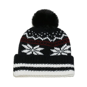 Close-up of black knit beanie with white snowflake jacquard patterns and pom-pom detail