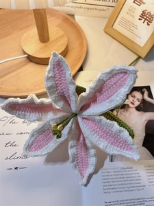 Detail of hand-knitted white and pink lily flower with crochet texture and green stem