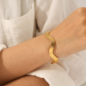 Bracelet jon jonc ondulé en acier doré avec gravures d'étoiles et petits diamants au poignet