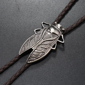 Macro detail of vintage silver cicada bolo tie pendant with dark brown woven cord