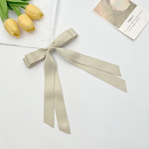 Close-up of champagne satin bow hair clip with long ribbons and silky texture finish