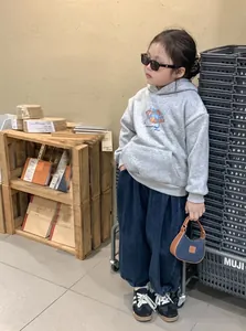 Sac à main enfant léopard tendance porté avec un sweat gris et un jean sur modèle