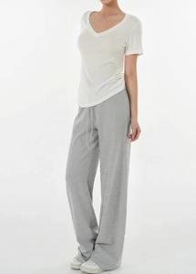 Detail view of Tencel wool blend fabric on white V-neck T-shirt and striped wide-leg trousers