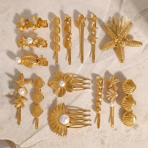 Golden starfish and shell hair clips with pearls set on a textured stone surface